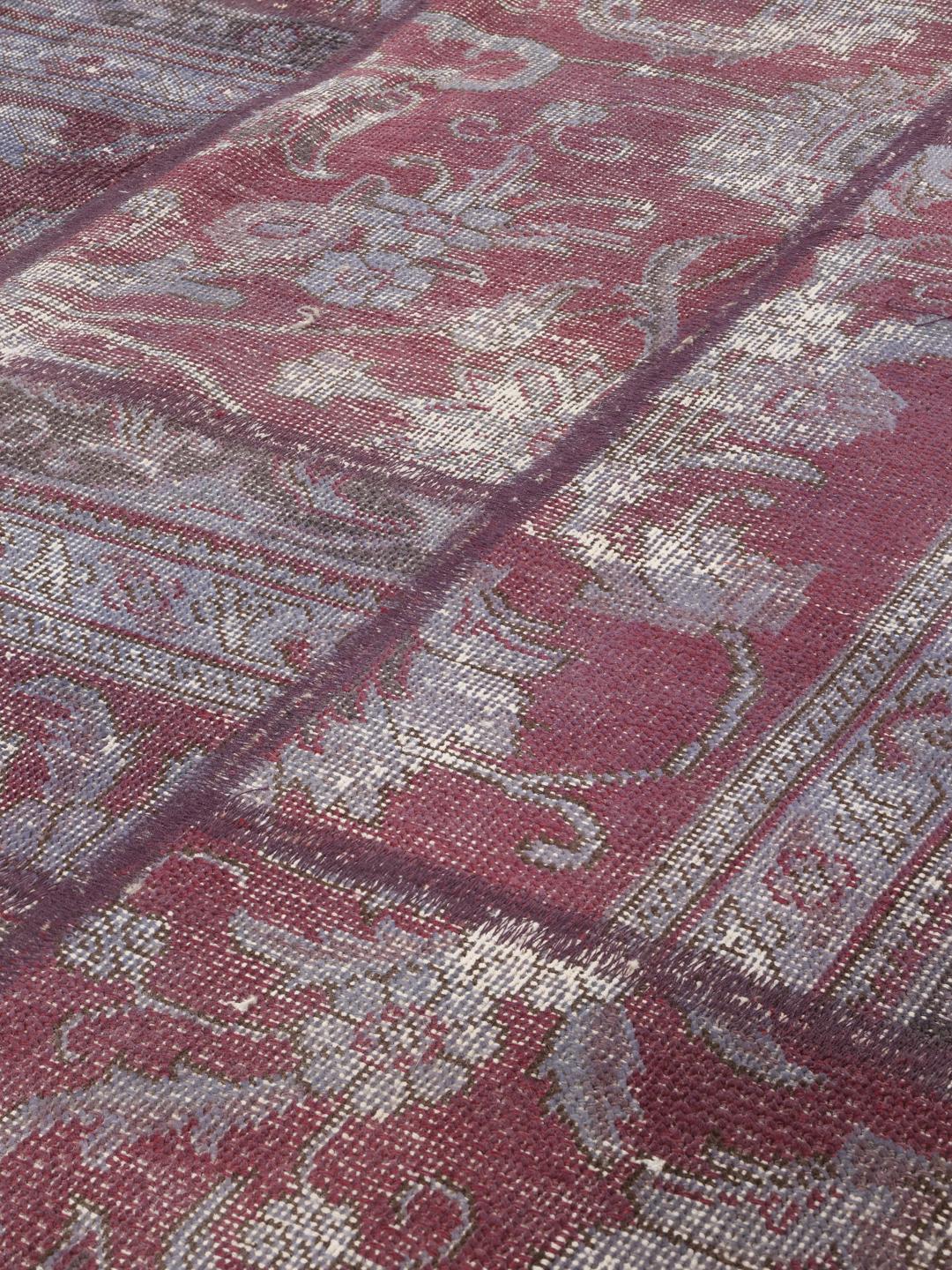 Et stort rektangulært patchwork-tæppe med en blanding af røde og dæmpede toner, der stammer fra Mellemøsten.
