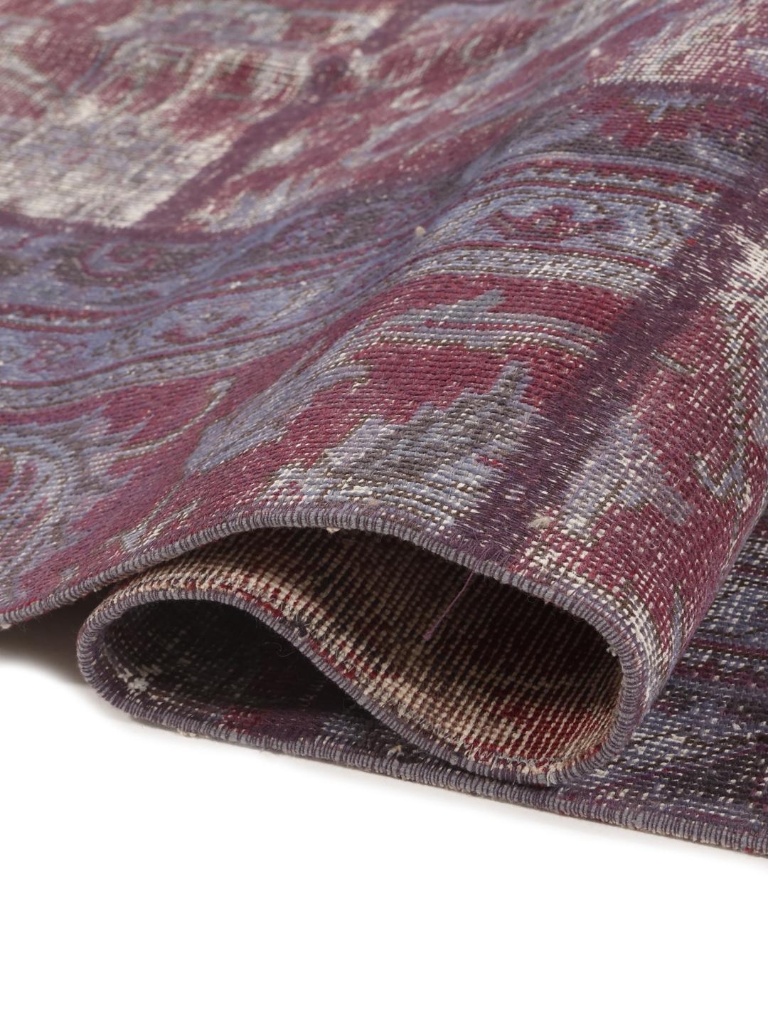 Et stort rektangulært patchwork-tæppe med en blanding af røde og dæmpede toner, der stammer fra Mellemøsten.