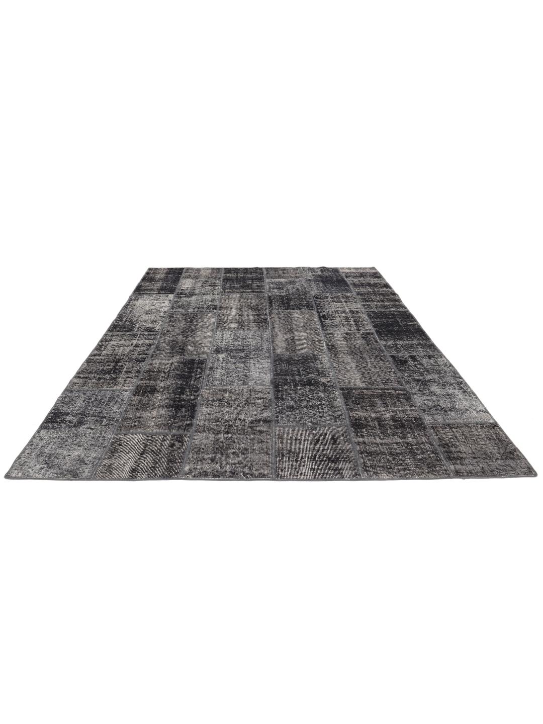 Een uniek, met de hand geknoopt patchwork vloerkleed uit Turkije in verschillende tinten donkergrijs.