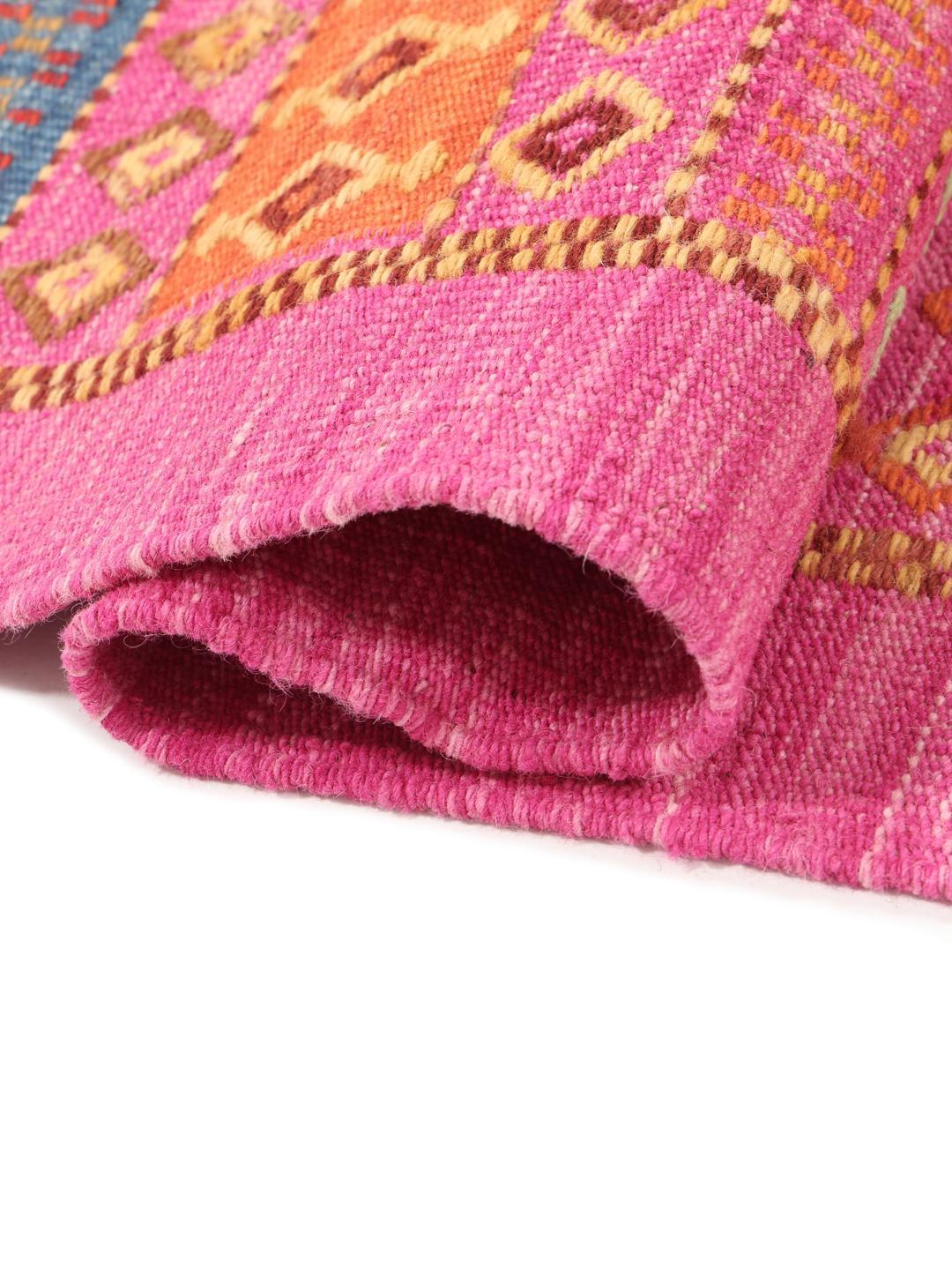 Handgeweven Afghaans Kelim tapijt in levendig roze met geometrische patronen.