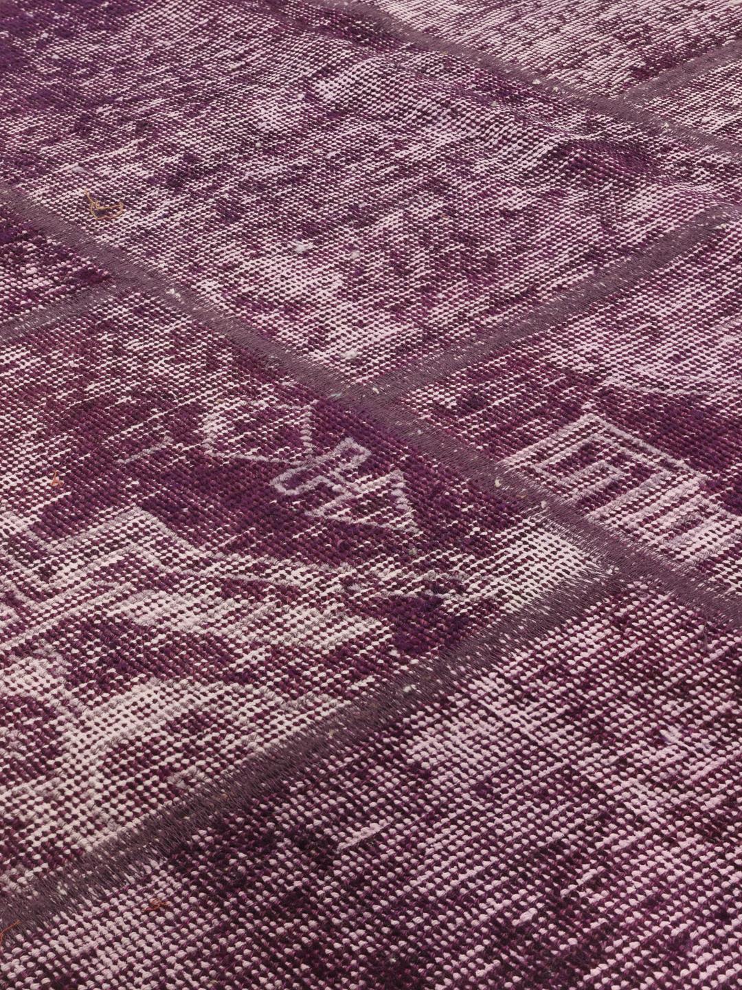Een vierkant patchwork vloerkleed uit het Midden-Oosten in paarse tinten.