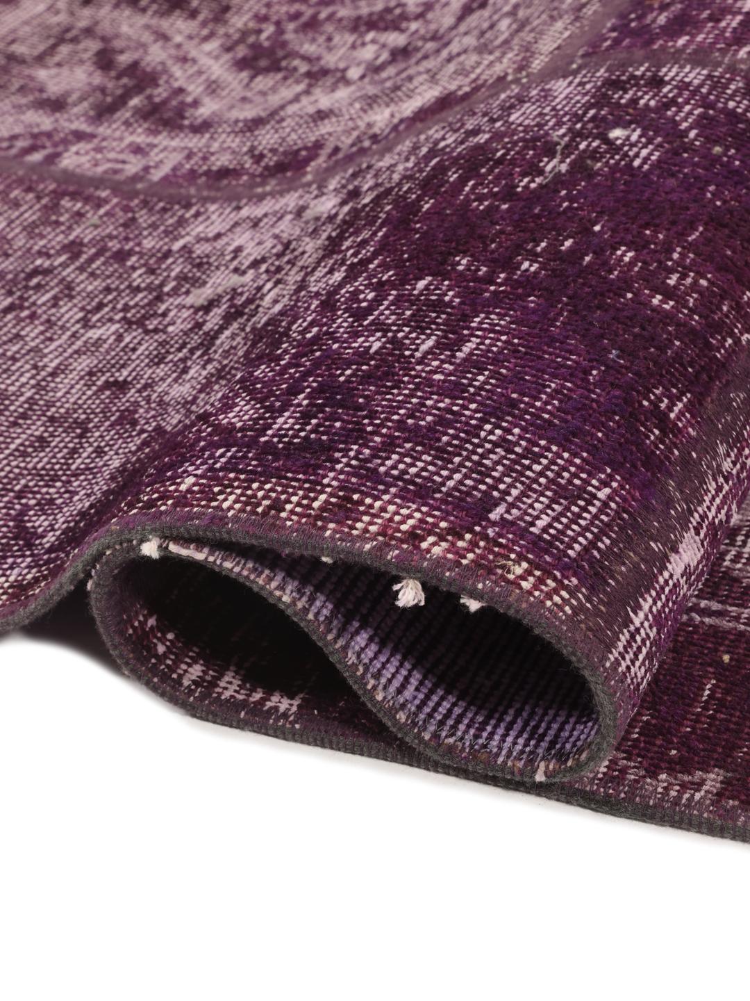 Een vierkant patchwork vloerkleed uit het Midden-Oosten in paarse tinten.
