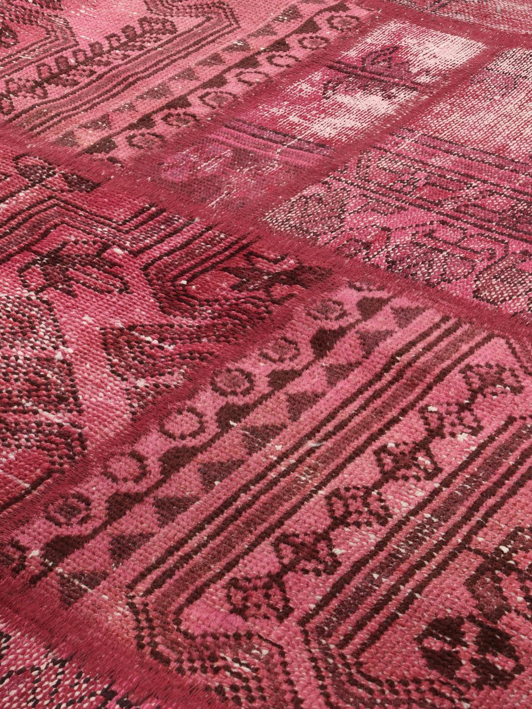 Een rond rood patchwork tapijt uit het Midden-Oosten met geometrische en florale patronen
