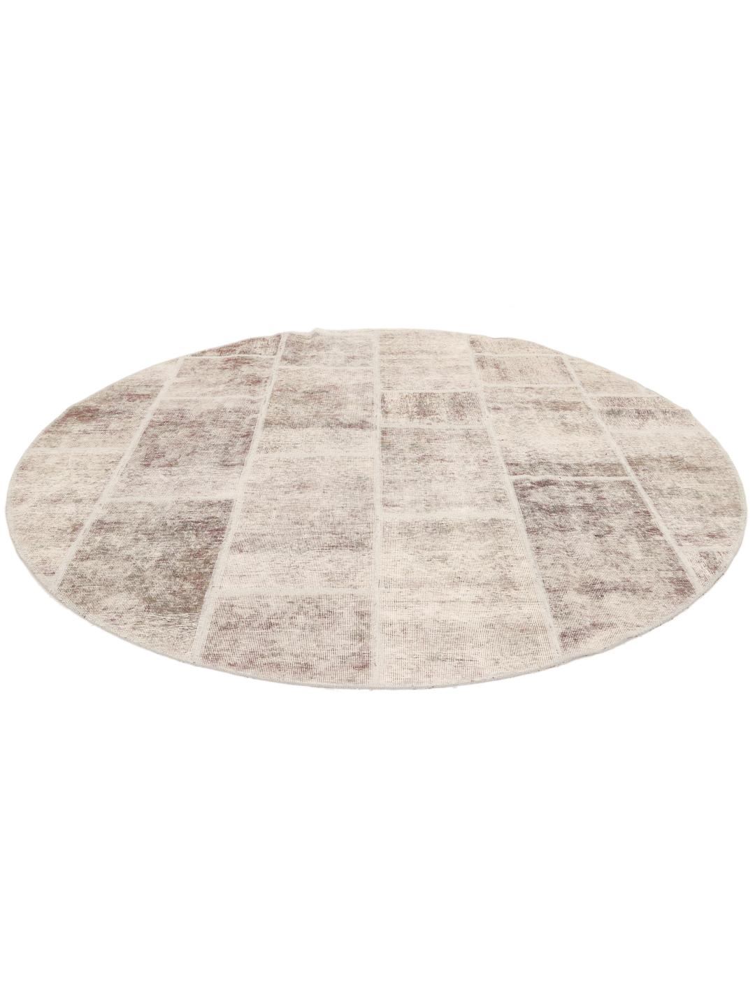 Een rond patchworktapijt in tinten beige en lichtbruin met een textuurrijk oppervlak.