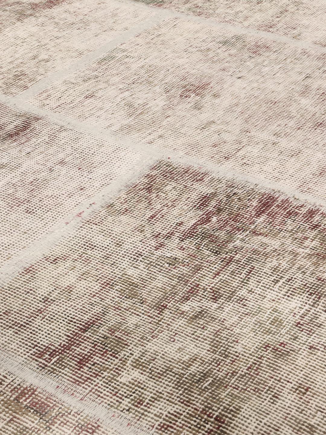 Een rond patchworktapijt in tinten beige en lichtbruin met een textuurrijk oppervlak.