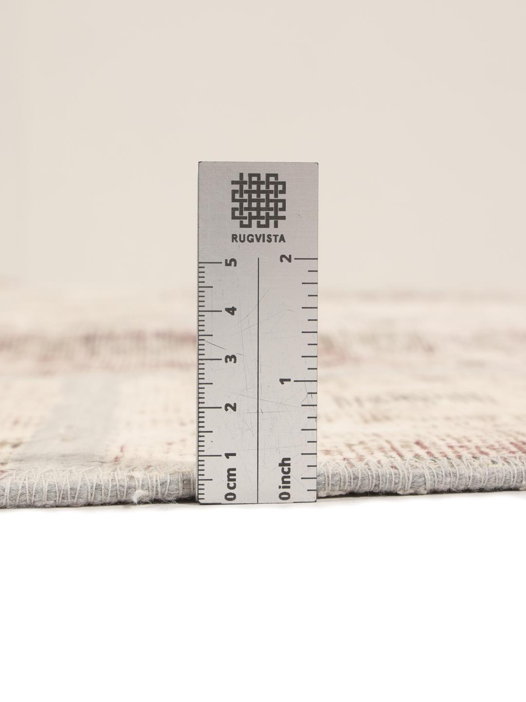 Een rond patchworktapijt in tinten beige en lichtbruin met een textuurrijk oppervlak.