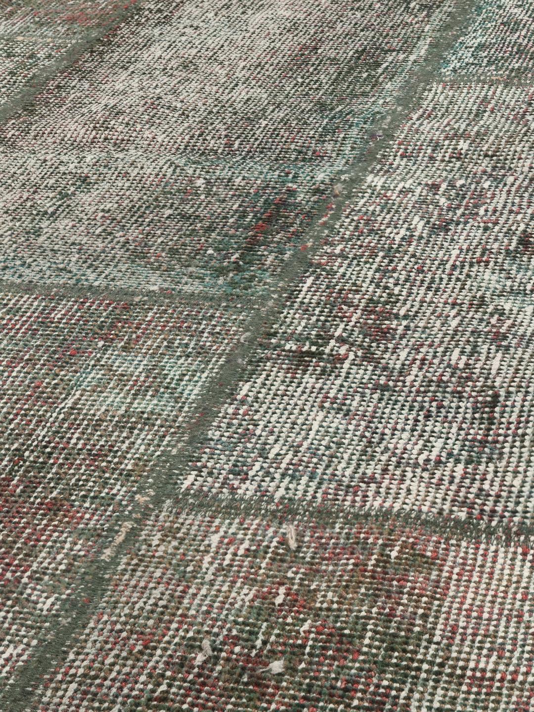 Et unikt rektangulært patchwork-tæppe med en mørkegrå og rød palet med oprindelse fra Mellemøsten.