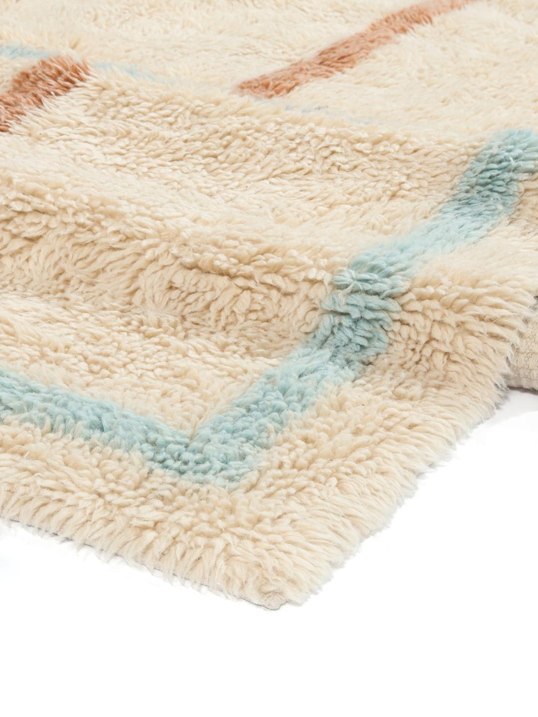 Beige tæppe med blød luv og et diskret flerfarvet ternet design