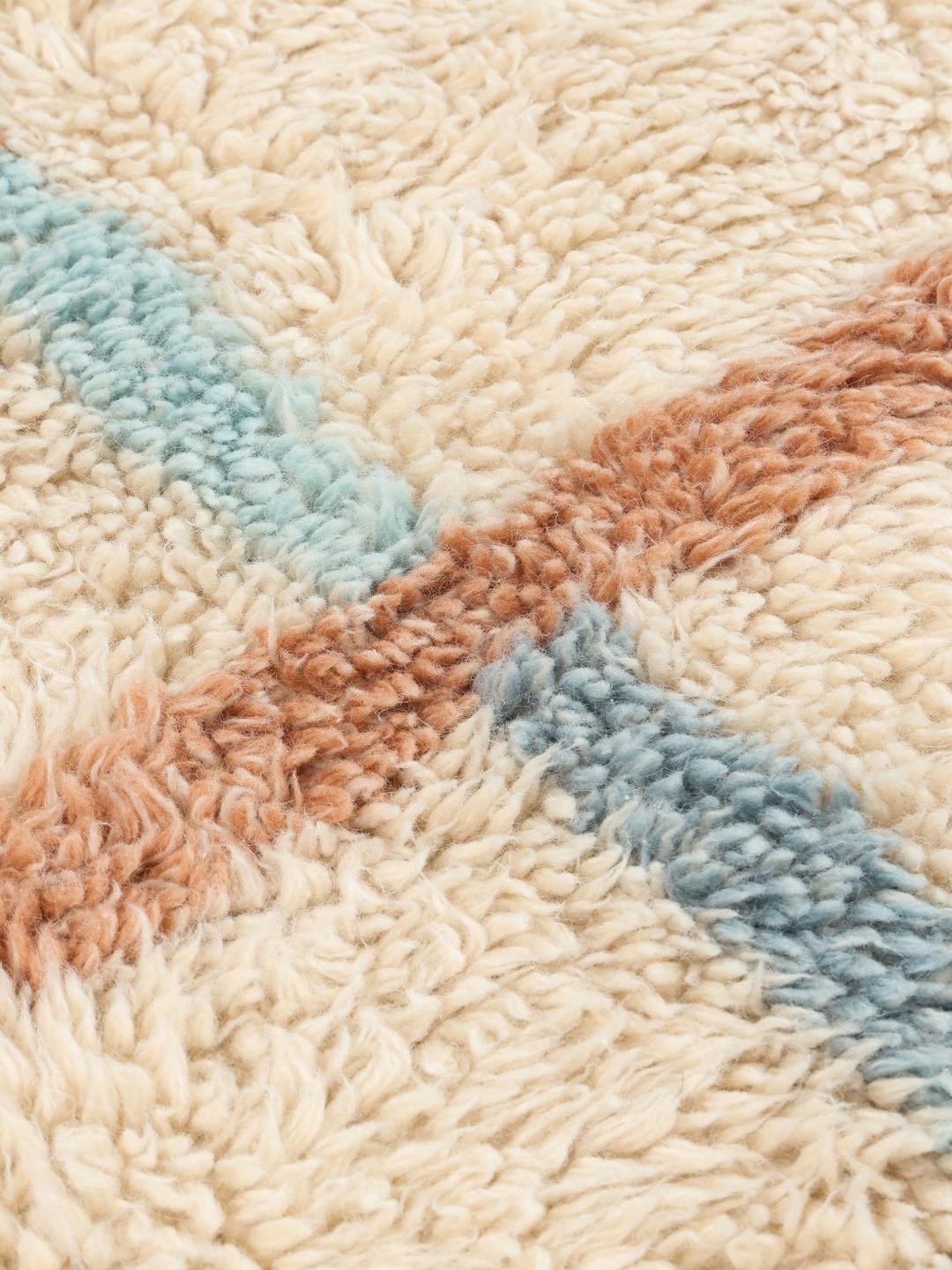 Beige tæppe med blød luv og et diskret flerfarvet ternet design