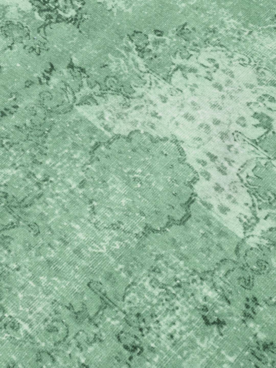 Rond groen vloerkleed met een verweerd patroon