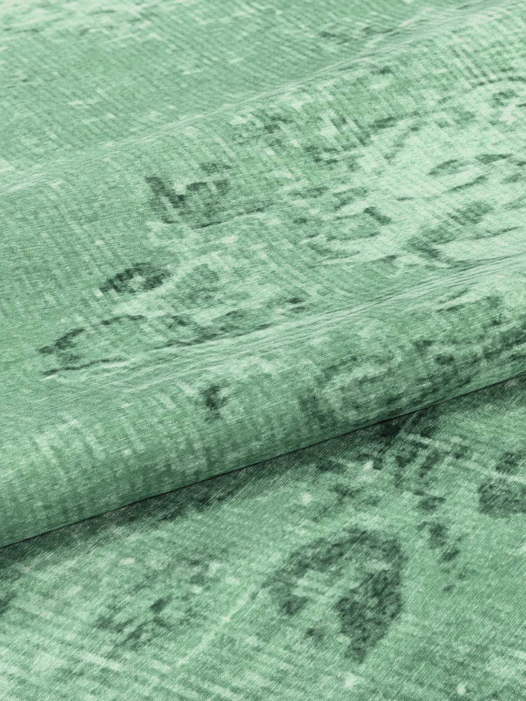 Rond groen vloerkleed met een verweerd patroon