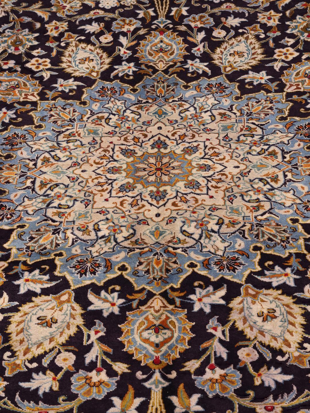 Un grand tapis Keshan rectangulaire noué à la main avec un champ bleu profond et un motif de médaillon floral complexe provenant du Moyen-Orient.