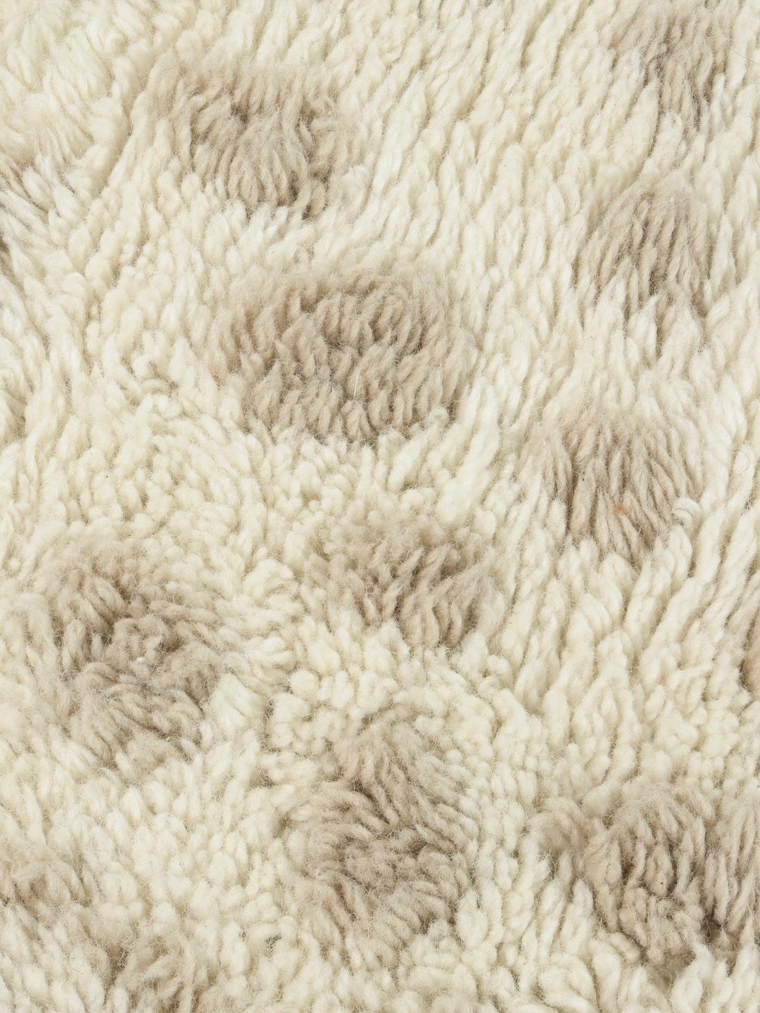 Onregelmatig gevormd wit en beige tapijt met een zachte pooltextuur