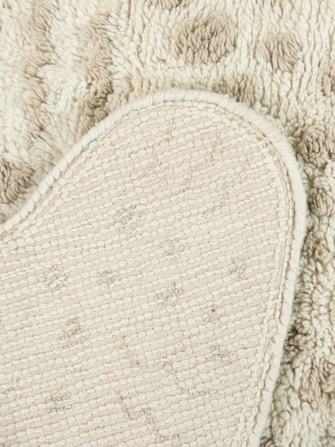 Onregelmatig gevormd wit en beige tapijt met een zachte pooltextuur