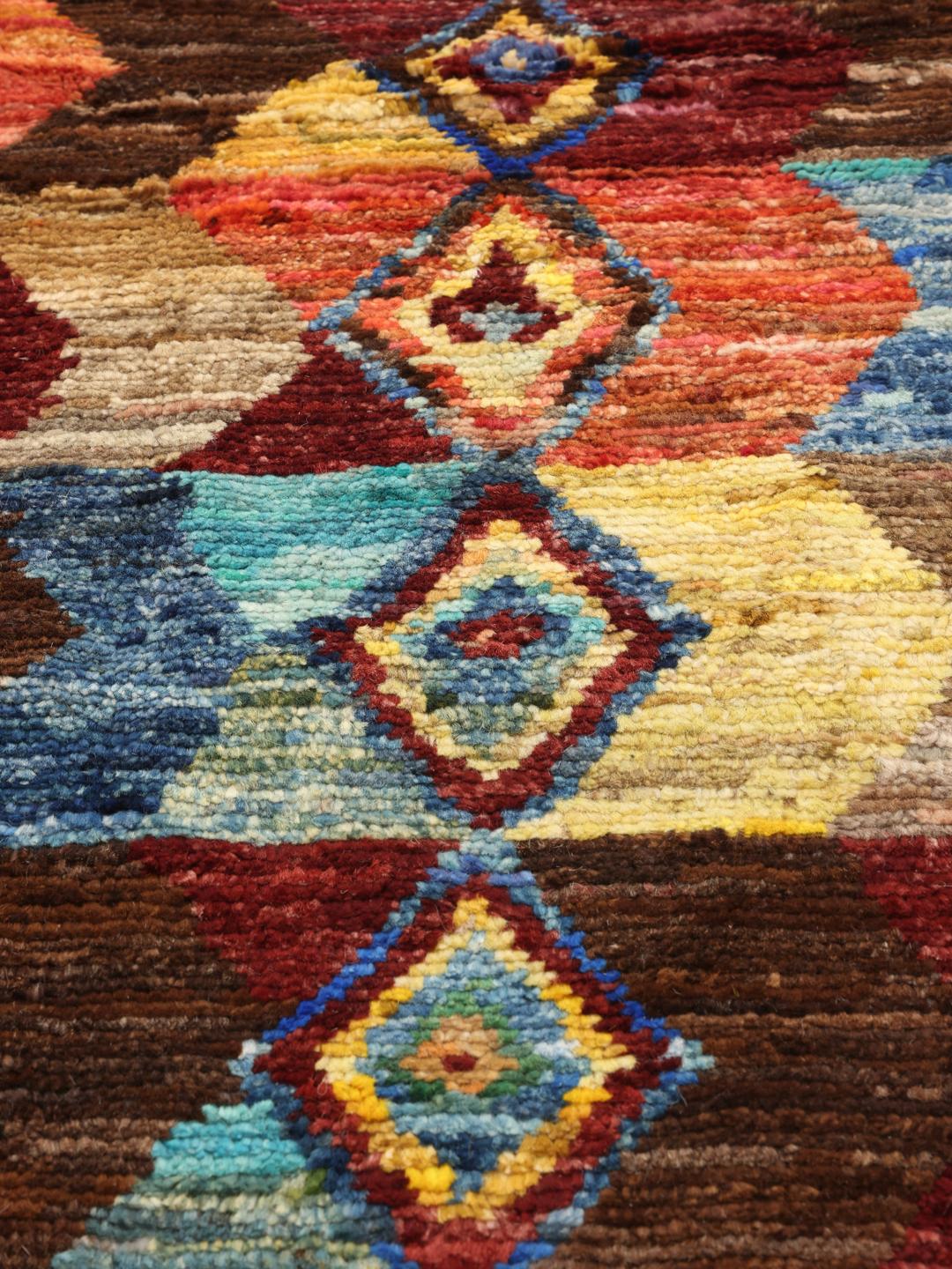 Een groot, rechthoekig, handgeknoopt Afghaans Berber-kleed met een levendig, veelkleurig chevron- en ruitpatroon.