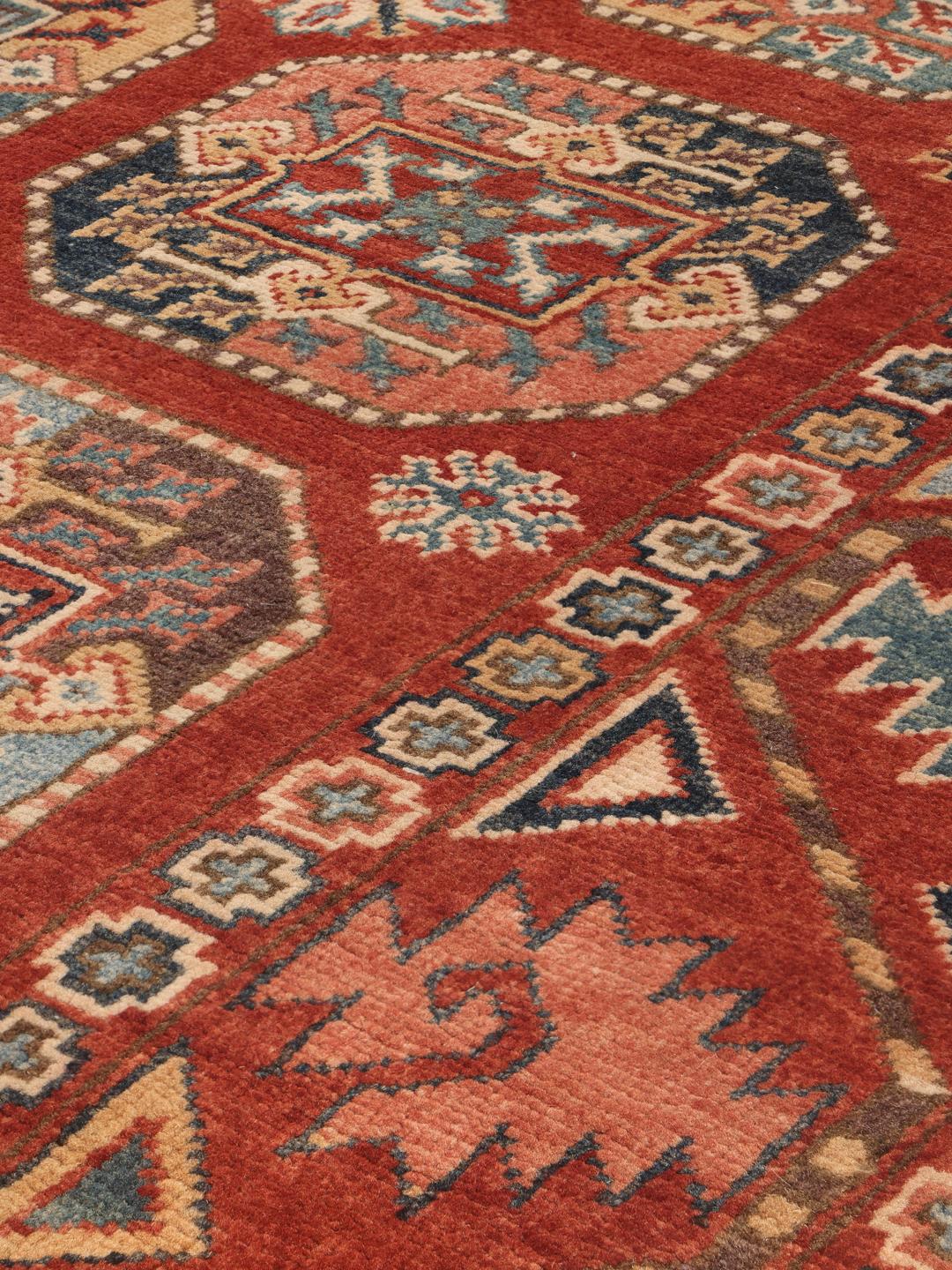 A hand-knotted Kazak rug from Afghanistan in deep red with geometric medallion motifs.