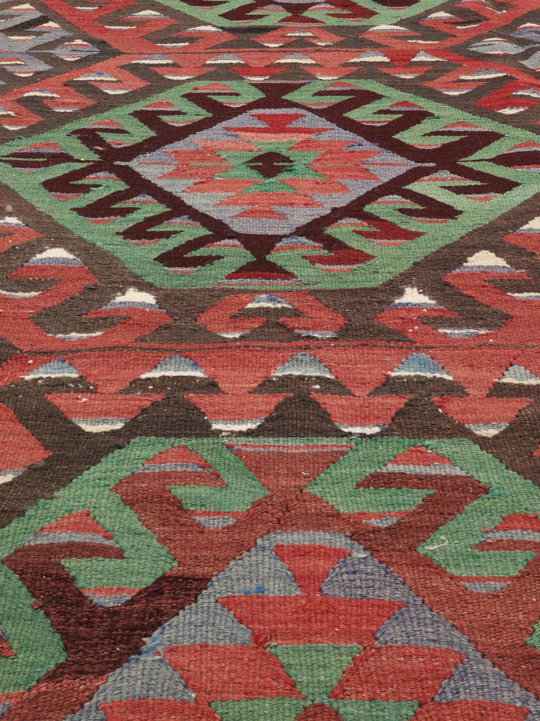 Un tapis Kelim turc vintage présentant un motif géométrique vibrant dans des tons de rouge, vert et bleu.