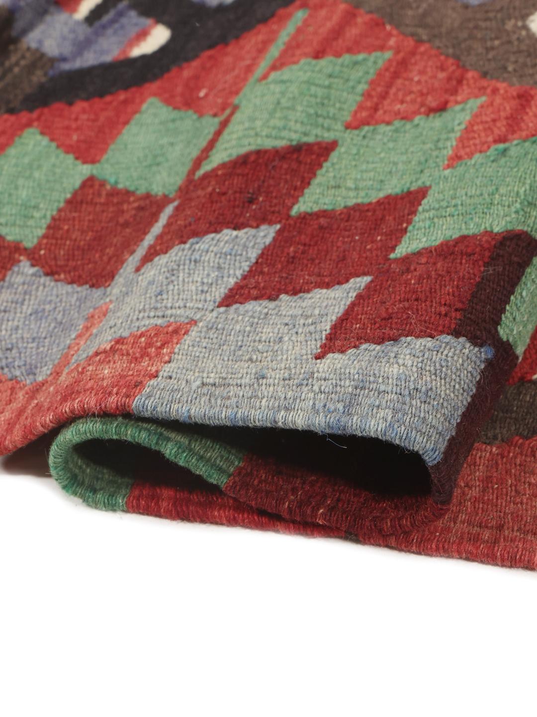 Un tapis Kelim turc vintage présentant un motif géométrique vibrant dans des tons de rouge, vert et bleu.