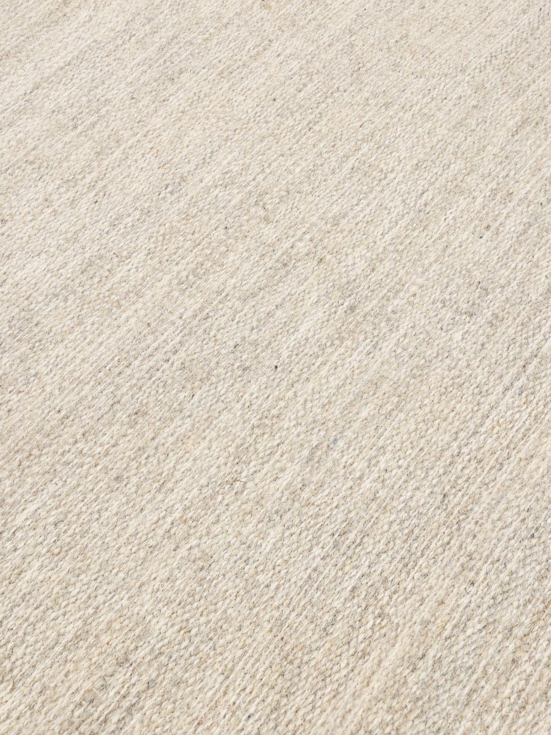 Beige tæppe med enkel vævet tekstur og frynsede ender