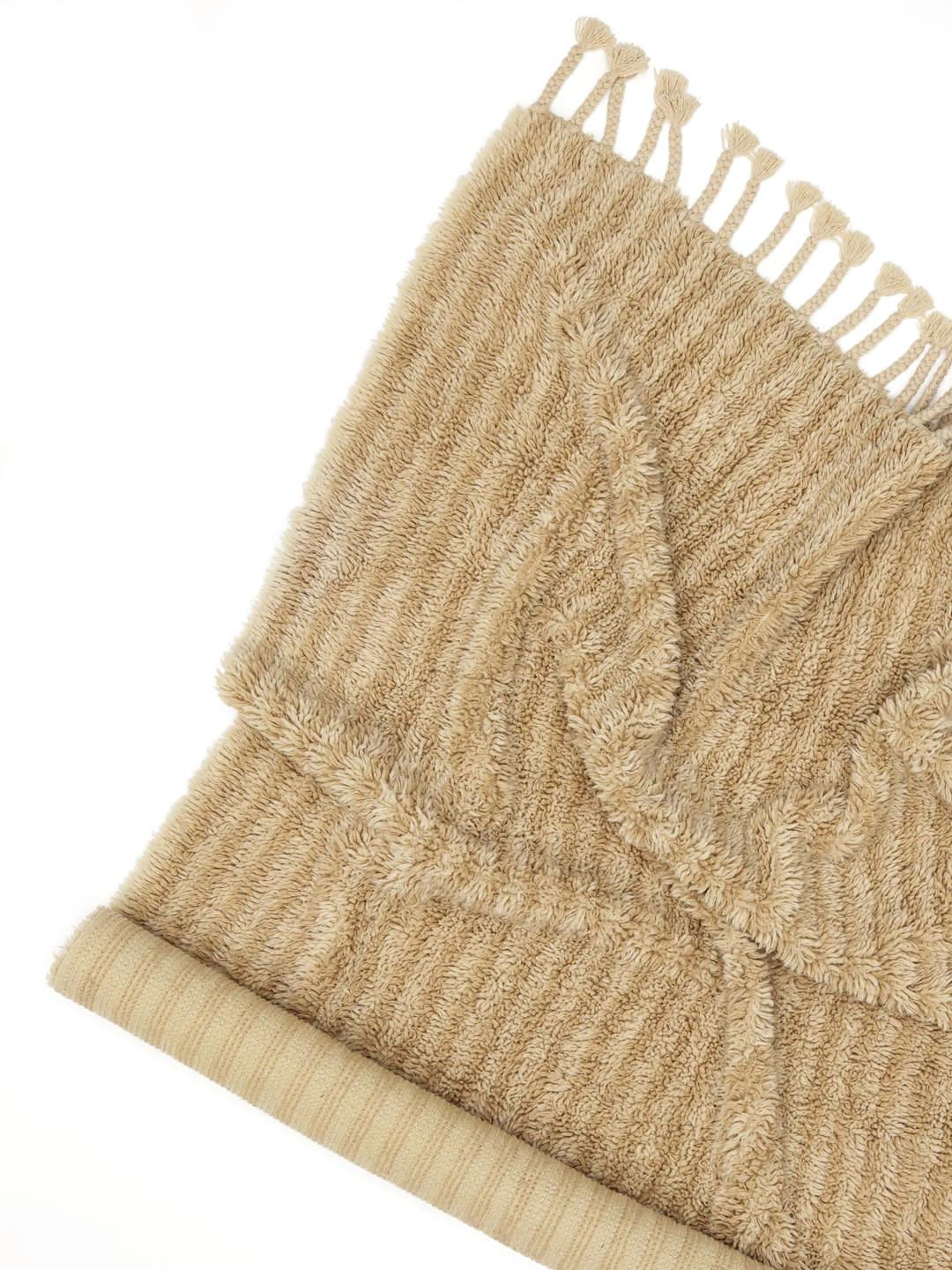 Beige tæppe med riflet tekstur og frynser