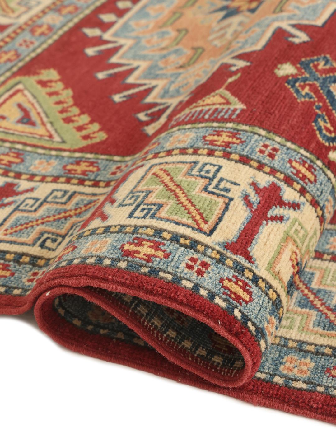 Een handgeknoopt Kazak-tapijt uit Afghanistan met een rood veld en geometrische medaillons.