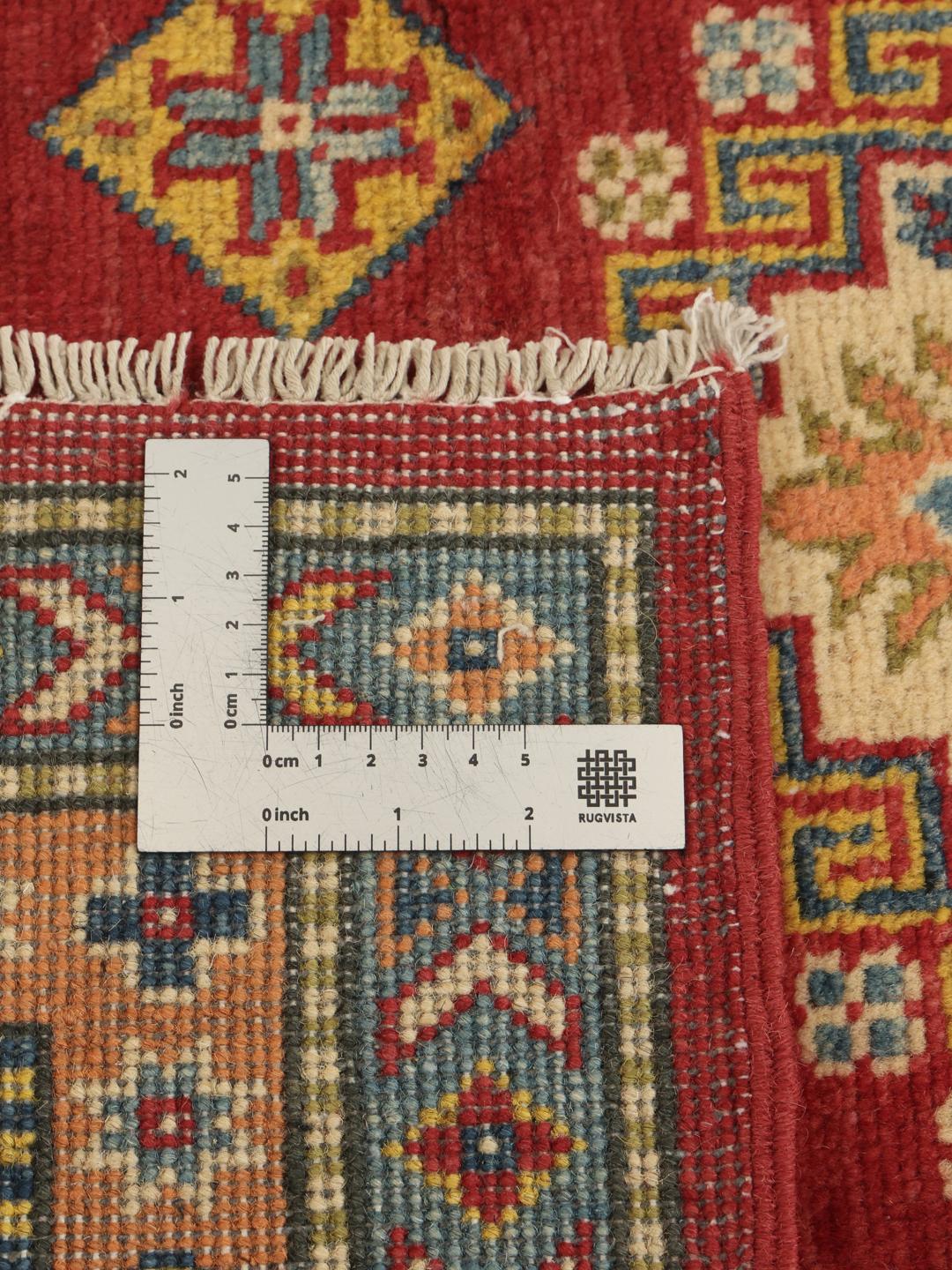 Un covor Kazak înnodat manual din Afganistan, având un câmp roșu vibrant și modele geometrice de medalion.