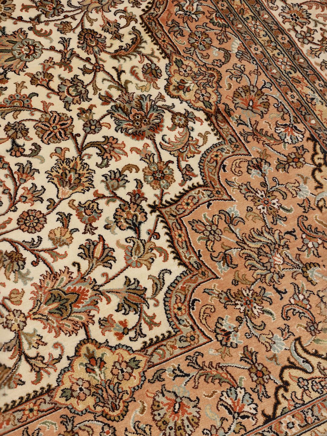 A hand-knotted Indian Kashmir silk rug with an intricate beige and floral pattern.