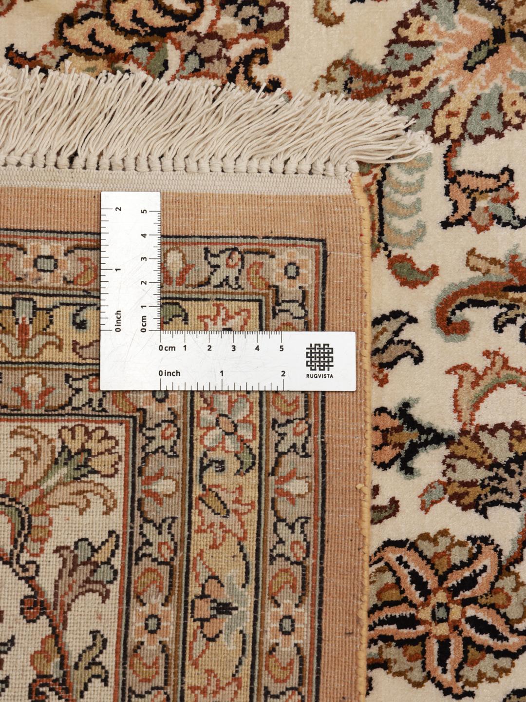 A hand-knotted Indian Kashmir silk rug with an intricate beige and floral pattern.