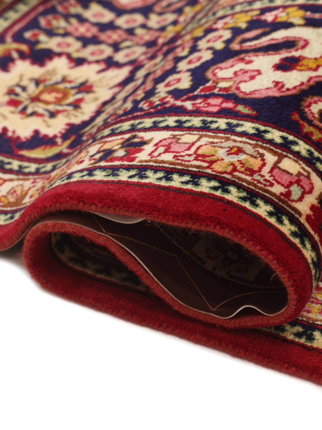 A large rectangular Tabriz rug with a deep red field and intricate floral patterns.