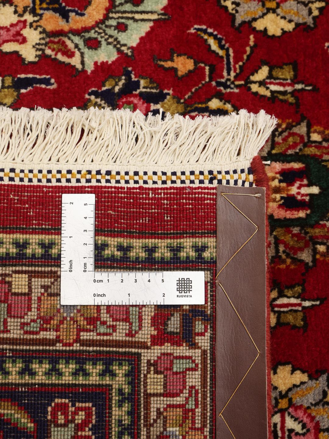 A large rectangular Tabriz rug with a deep red field and intricate floral patterns.