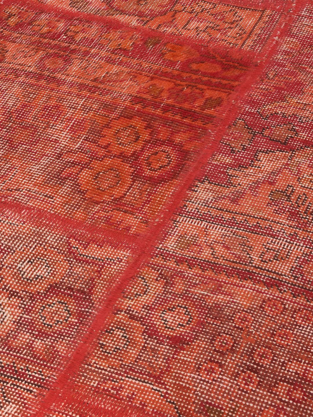 A red patchwork rug featuring various traditional Middle Eastern patterns and textures.