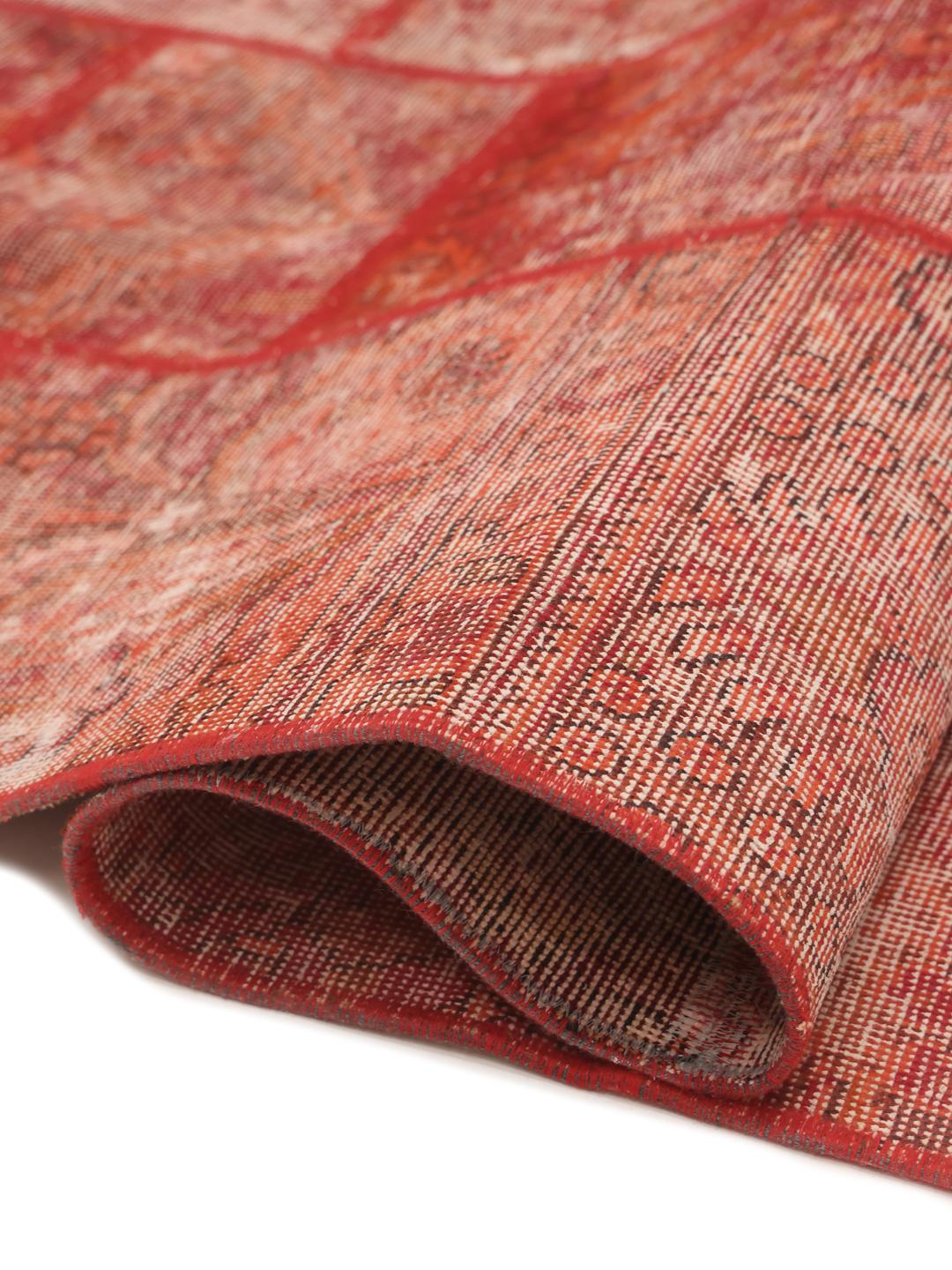 A red patchwork rug featuring various traditional Middle Eastern patterns and textures.