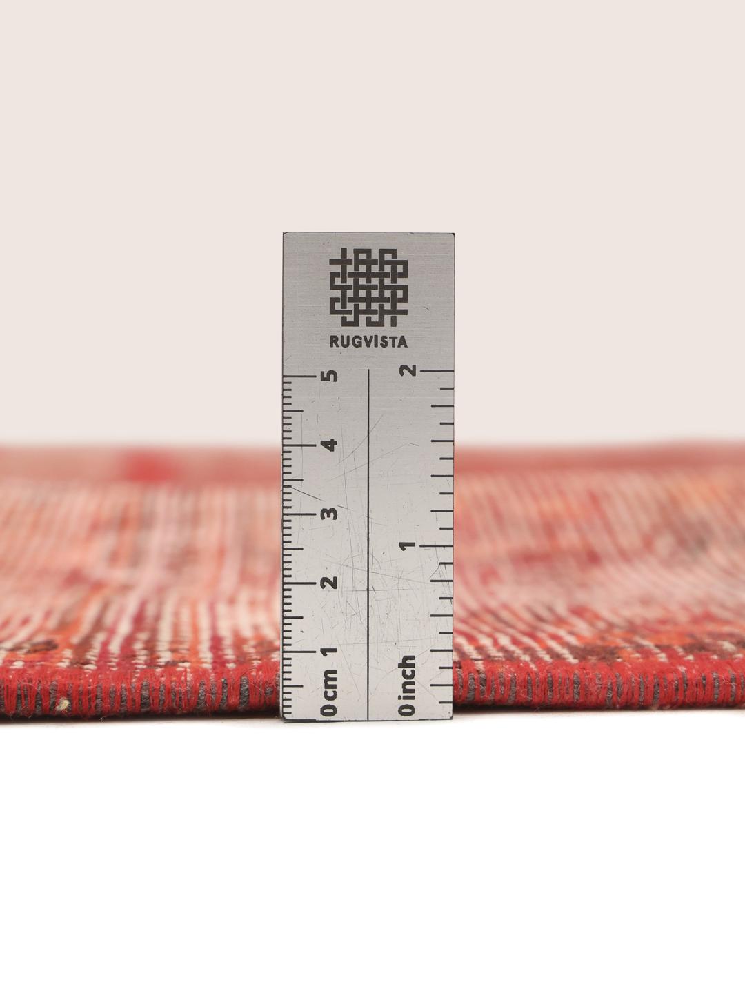 A red patchwork rug featuring various traditional Middle Eastern patterns and textures.