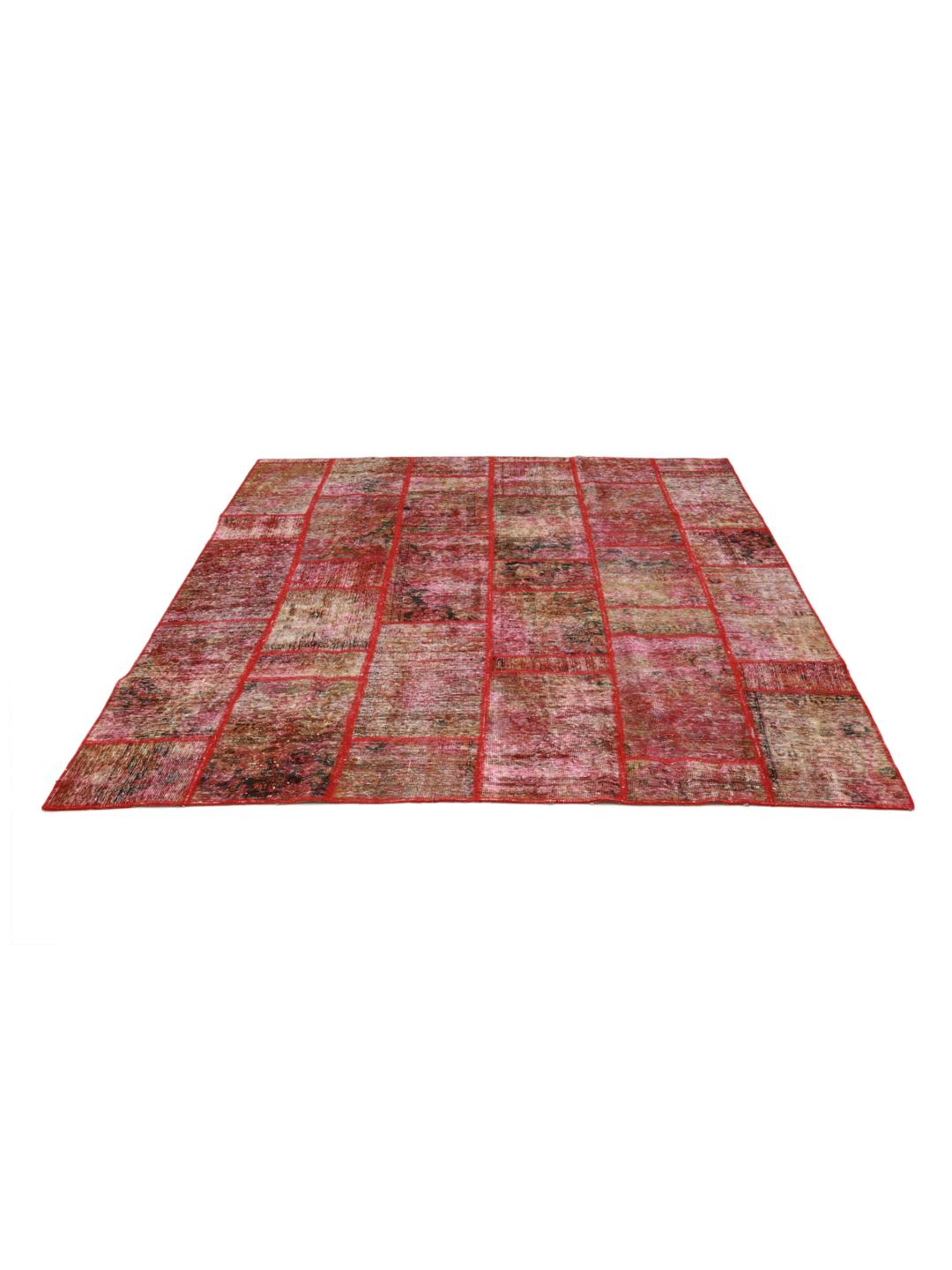 Un tapis patchwork rouge vibrant composé de fragments de laine noués à la main provenant du Moyen-Orient.