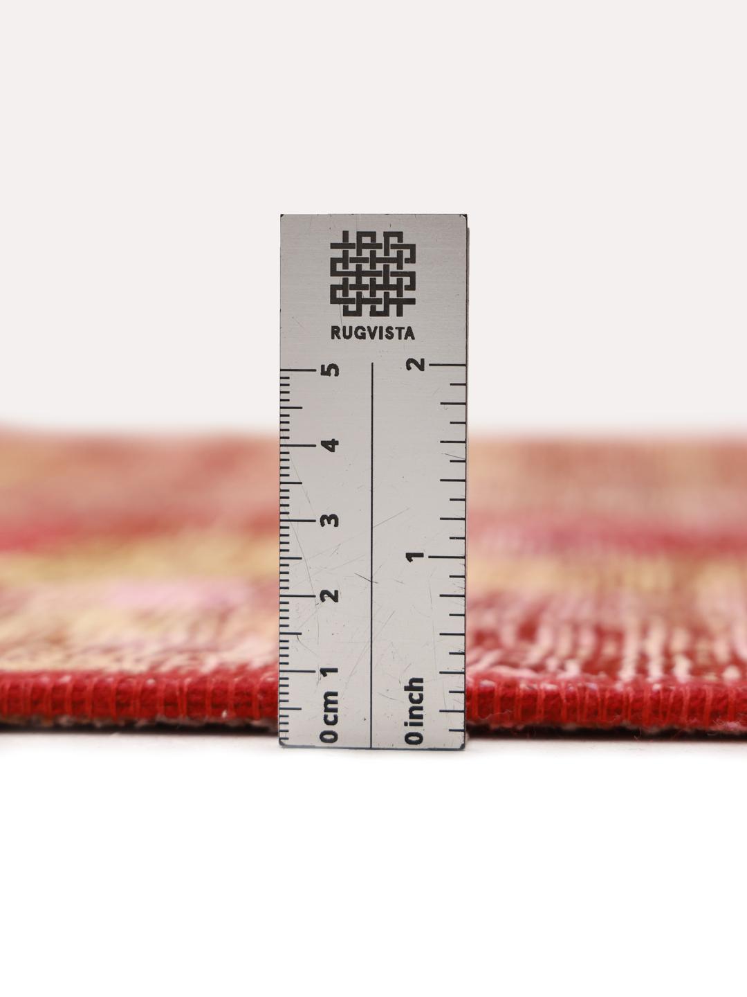 Et rundt patchworktæppe med et levende rødt og flerfarvet design, håndknyttet i Mellemøsten.