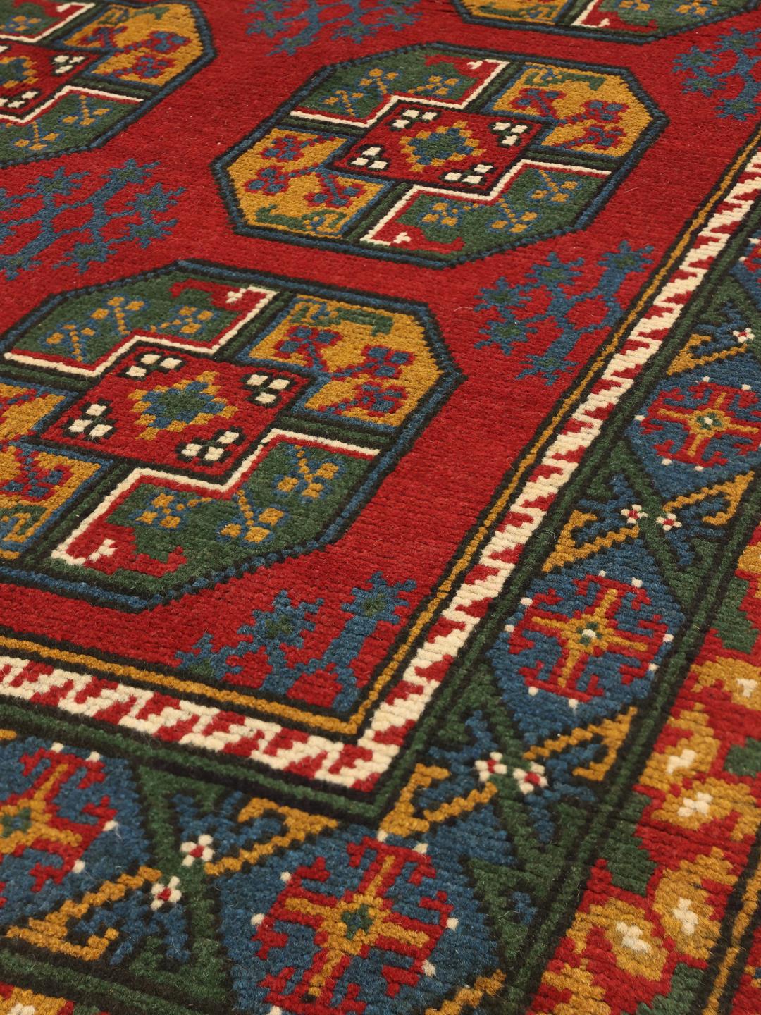 Håndknyttet afghansk tæppe i rødt med traditionelle geometriske motiver