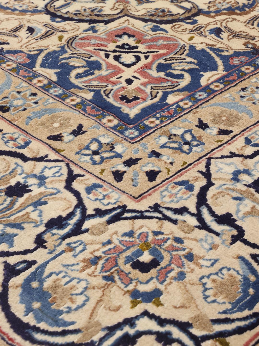 Hand-knotted Middle Eastern rug with intricate floral patterns in beige and blue