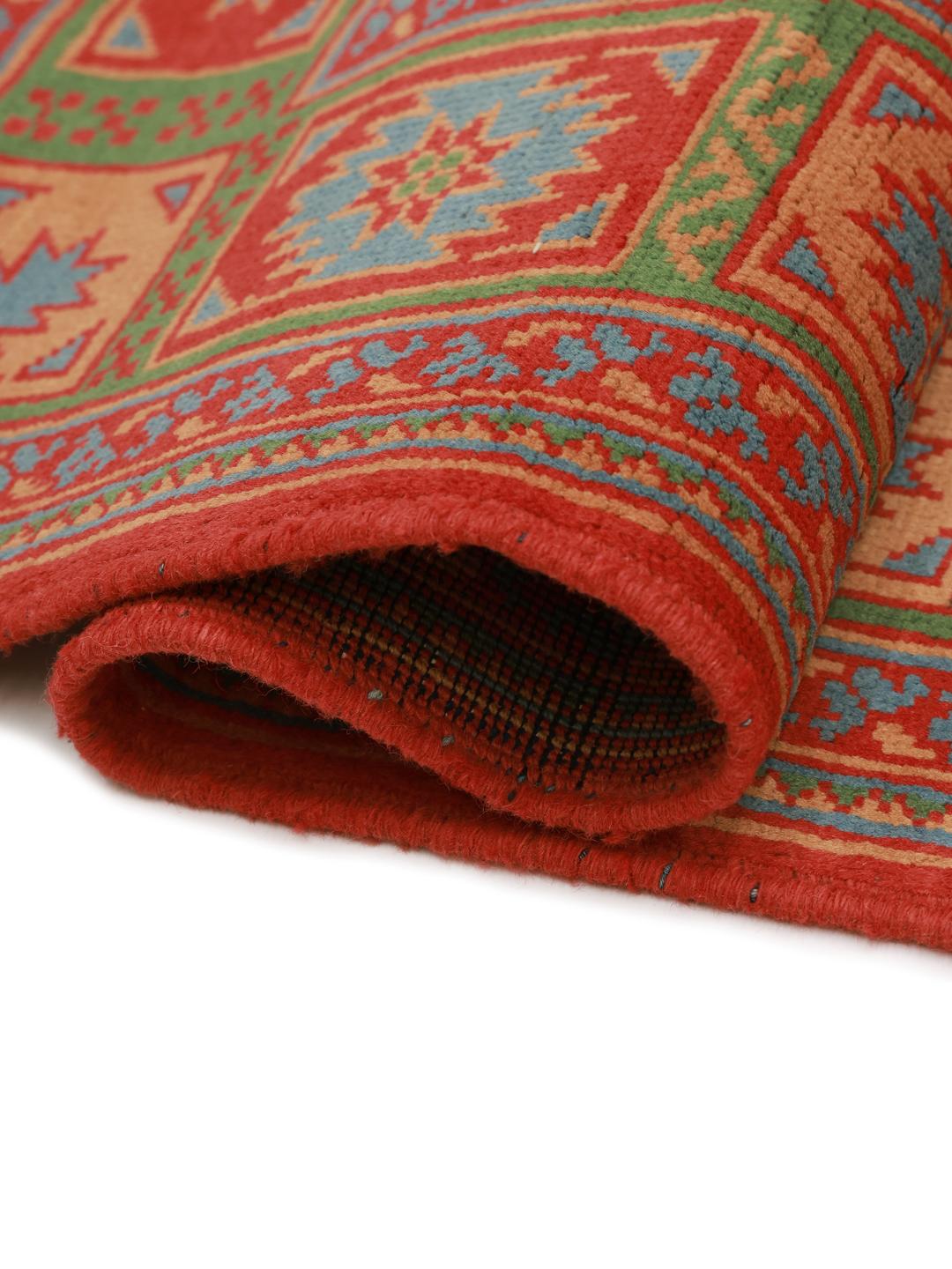 Håndknyttet afghansk tæppe med rød bund og traditionelle geometriske motiver