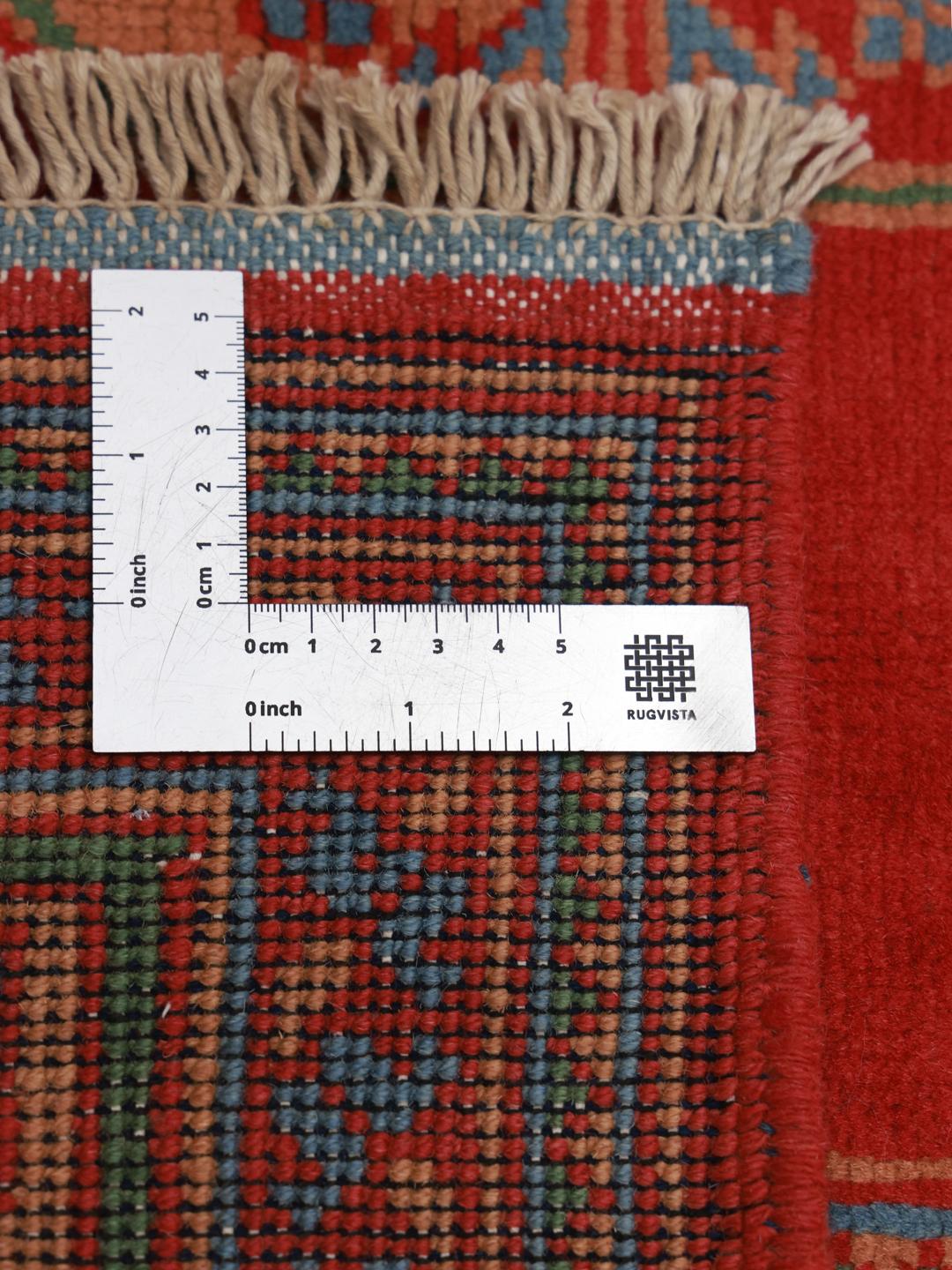 Håndknyttet afghansk tæppe med rød bund og traditionelle geometriske motiver