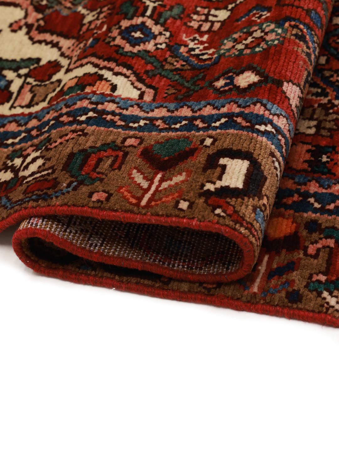 Et håndknyttet Hosseinabad-tæppe fra Mellemøsten med et rødt felt og traditionelle motiver.