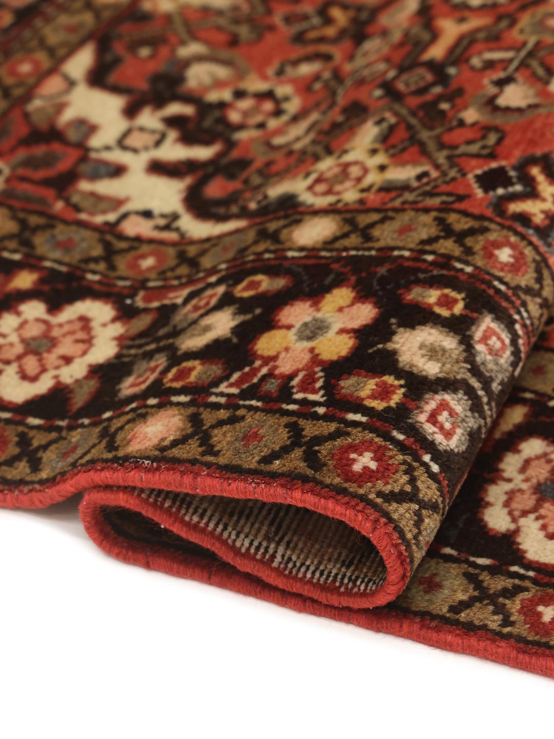 A hand-knotted Hosseinabad rug from the Middle East featuring a red and dark-toned floral design