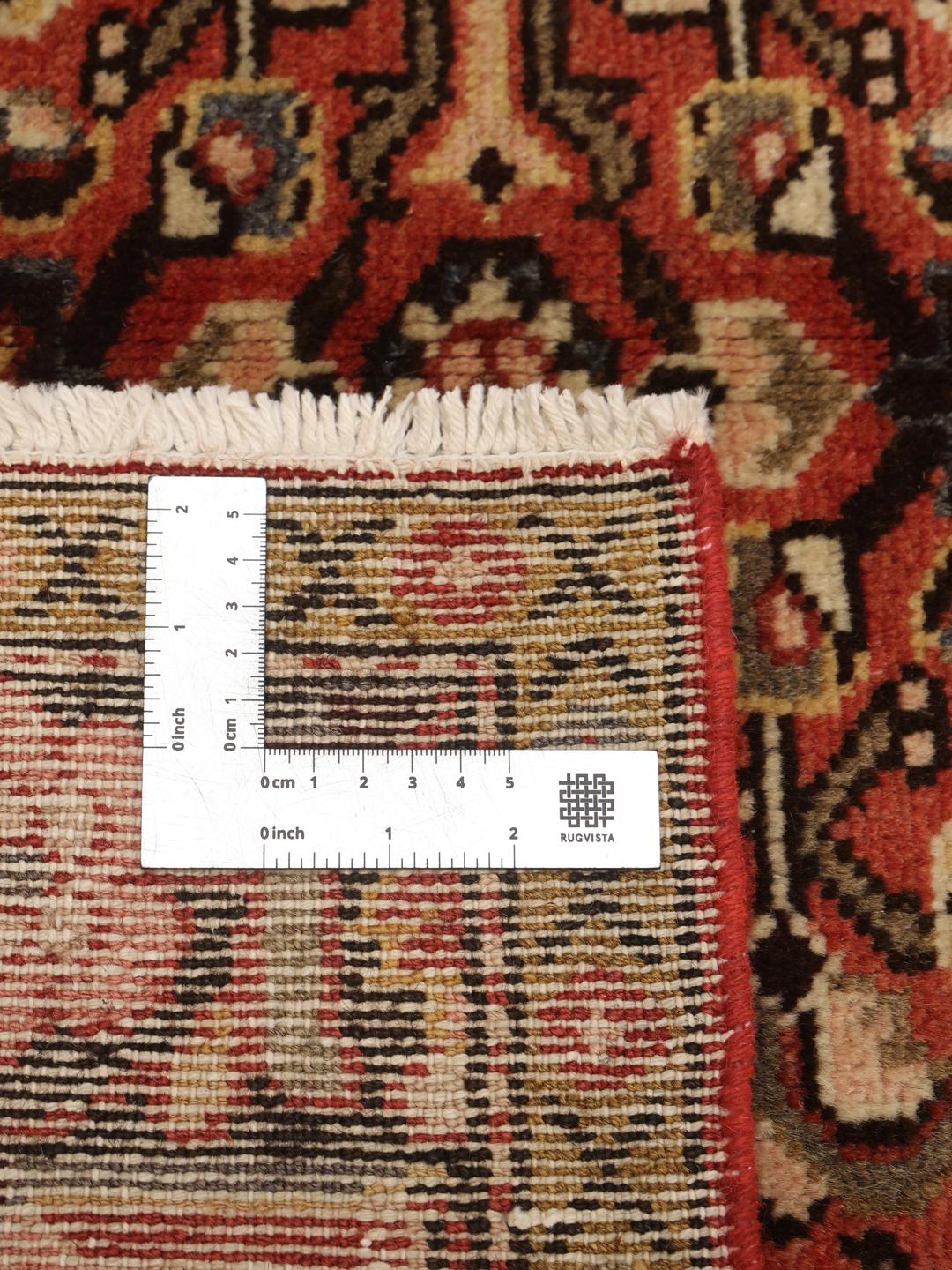 A hand-knotted Hosseinabad rug from the Middle East featuring a red and dark-toned floral design