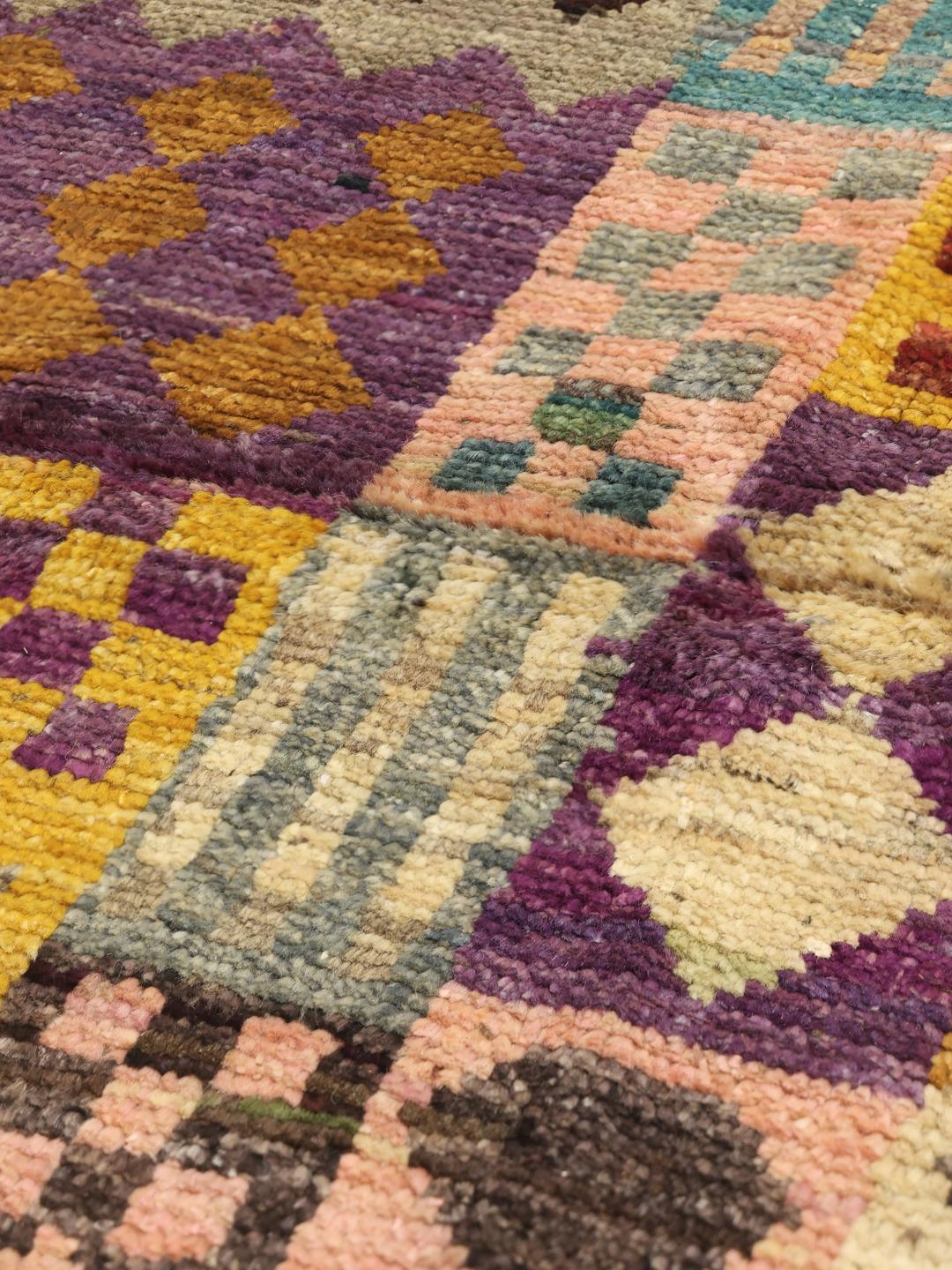 Et levende, håndknyttet Berber-tæppe fra Afghanistan med et farverigt, geometrisk patchwork-design.