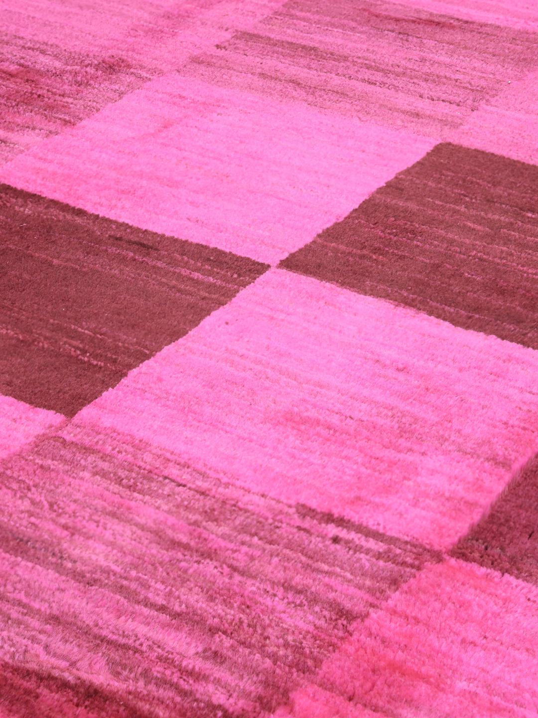 Et håndknyttet Gabbeh tæppe fra Mellemøsten med et levende skakternet mønster i pink og brun.