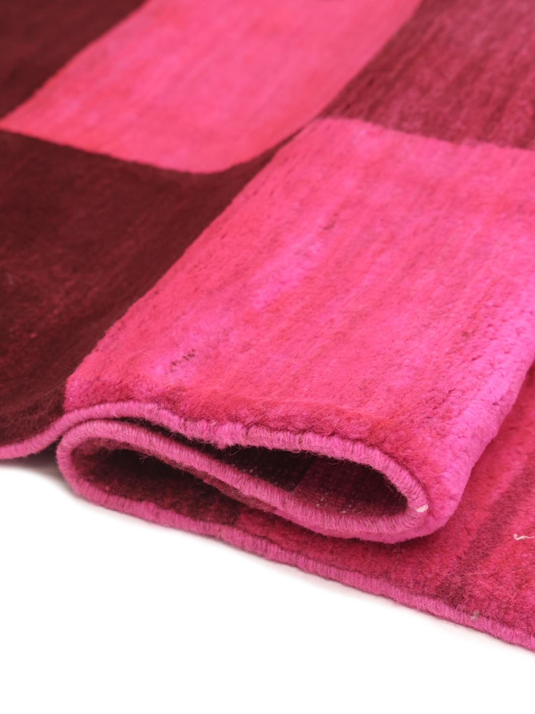 Et håndknyttet Gabbeh tæppe fra Mellemøsten med et levende skakternet mønster i pink og brun.