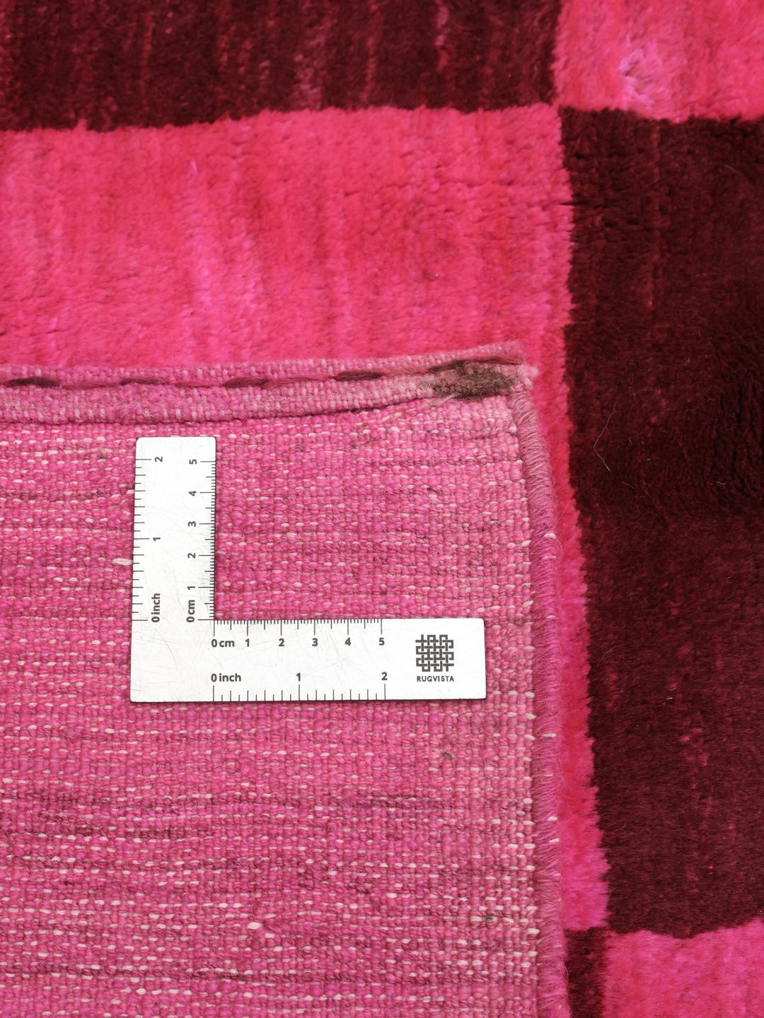 Et håndknyttet Gabbeh tæppe fra Mellemøsten med et levende skakternet mønster i pink og brun.