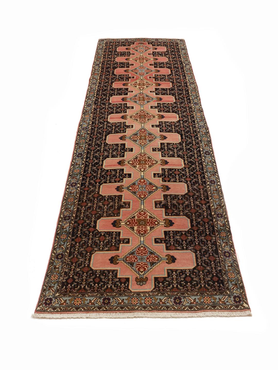 A hand-knotted Senneh runner with a multicolored diamond pattern on a dark field.