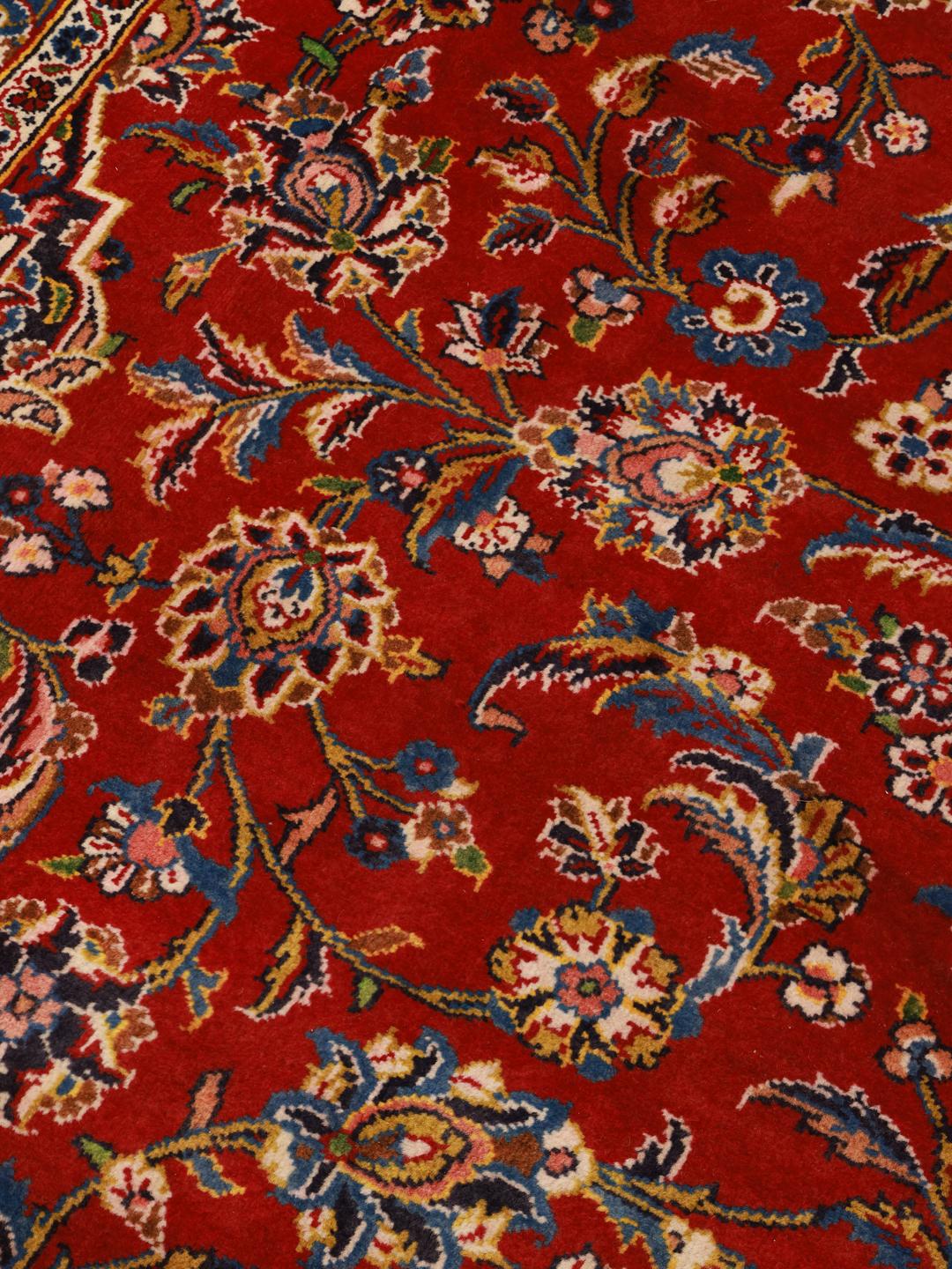 A large, hand-knotted Keshan rug from the Middle East with a red field and ornate floral patterns.