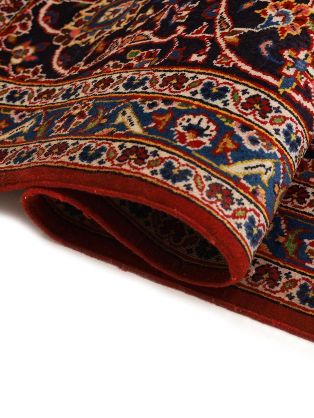 A large, hand-knotted Keshan rug from the Middle East with a red field and ornate floral patterns.