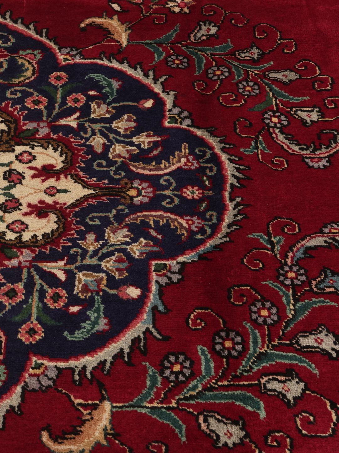 Handmade Tabriz rug with a red field and intricate blue floral medallion from the Middle East